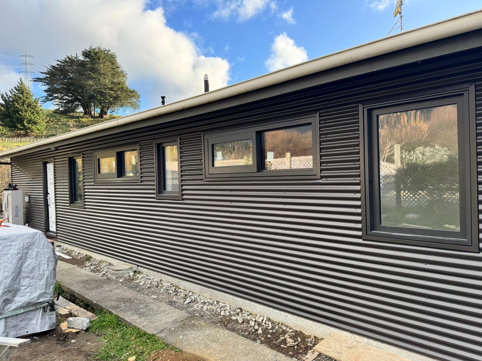 Dark horizontal corrugated metal wall cladding with newly fitted windows on a Wellington building