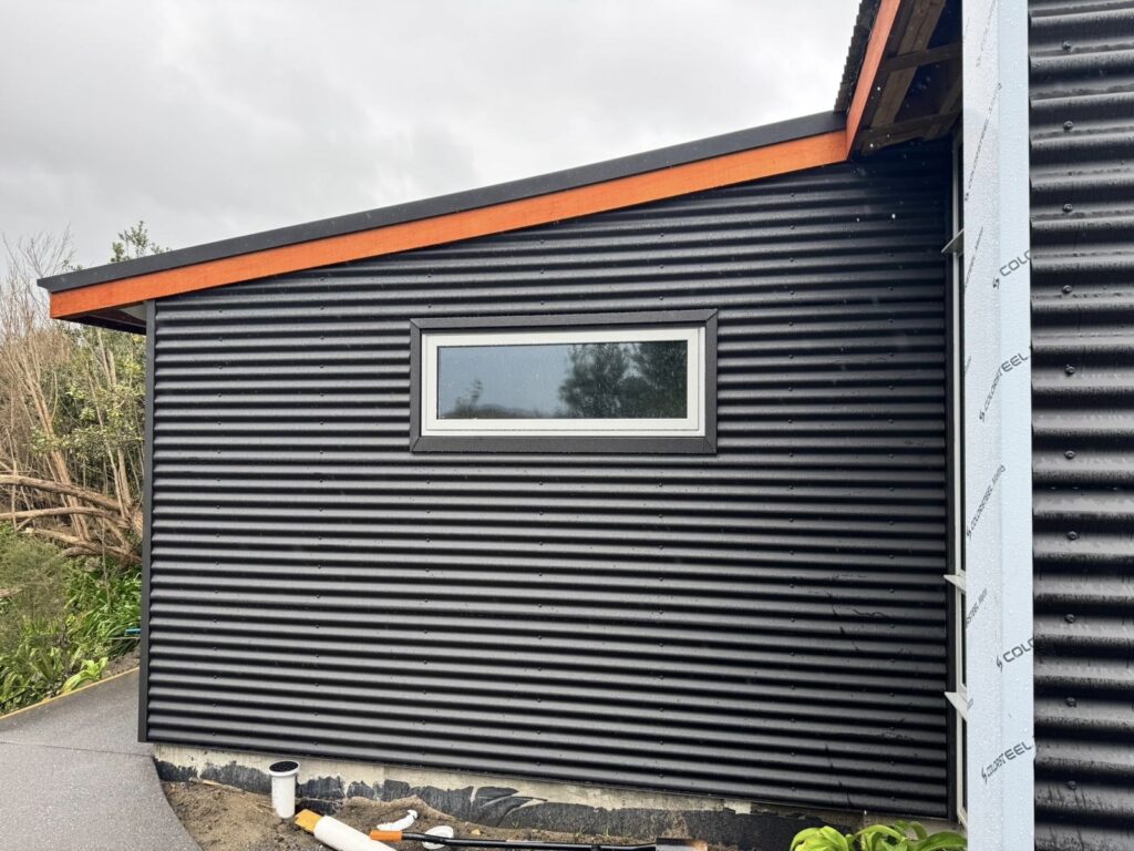 Dark horizontal corrugated metal wall cladding fitted around a rectangular window opening