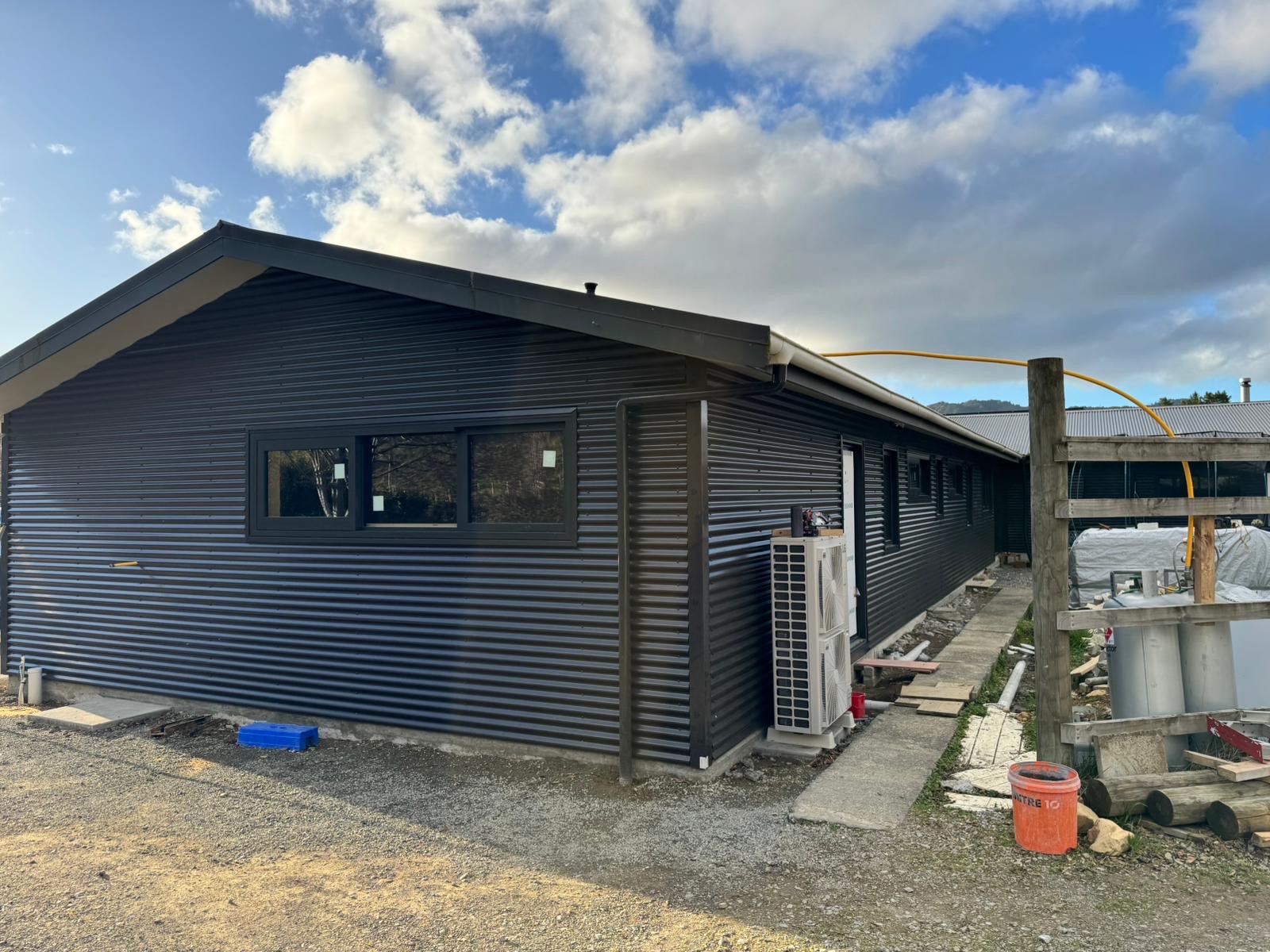 Wide view of a low Wellington-region building finished in dark horizontal corrugated metal cladding