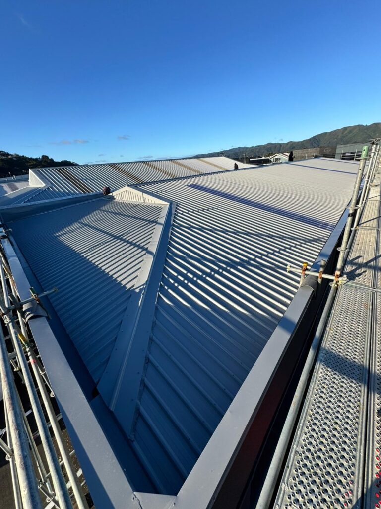 Completed silver long-run metal roof with new flashings and scaffolding on a Wellington property