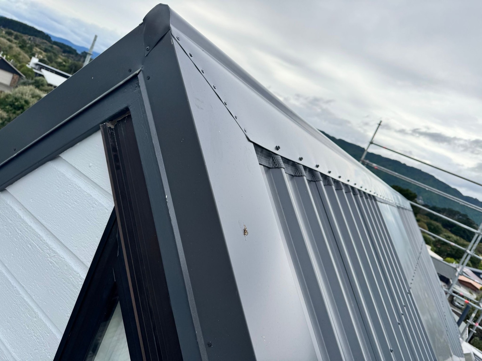 Close view of dark folded barge flashing finishing a light metal roof at a Wellington gable